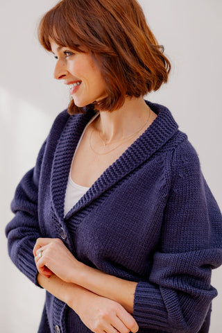 Woman wearing a Navy knitted cardigan against a plain background