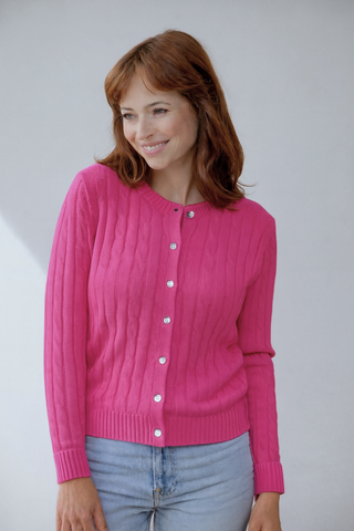 Woman wearing a pink cardigan against a plain background